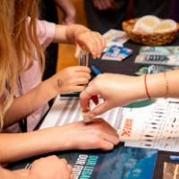 students getting a stamp from another student presenter at their exhibit table